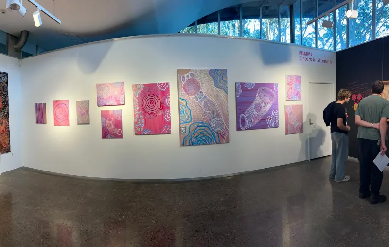 A full hang of Renae Lamb’s pink works, with visitors in the space