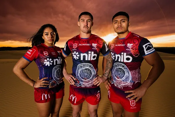 Three Knights players shoulder to shoulder in the Indigenous jersey at sunset