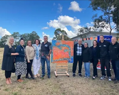 A community group with a finished painting, on Country