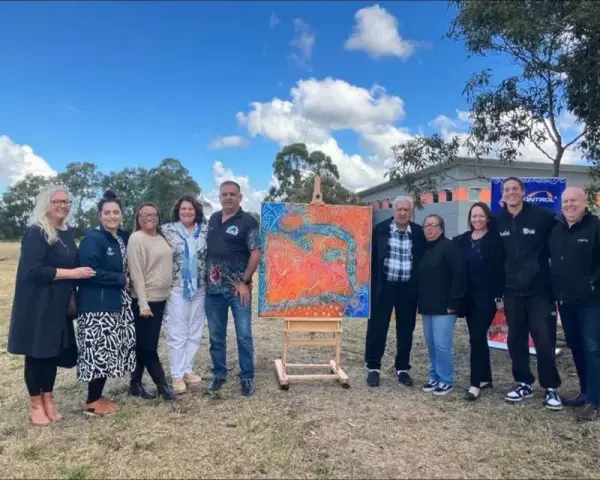 A community group with a finished painting, on Country
