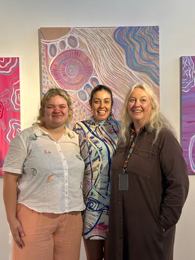 Three visitors in front of a large lilac work by Renae Lamb