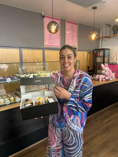 Renae Lamb in her own print, her framed works behind the counter